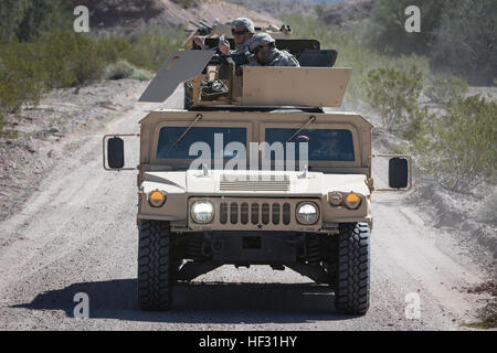 Arizona Army National Guard Spc. Juan Yepez feuert eine leichtes Maschinengewehr M249 aus dem Turm ein M-1151 Humvee während Staff Sgt Matthew Curtis, eine Palette Sicherheitsfachkraft, Filme, die die Aktion auf ein Handy in einem Konvoi scharfer Munition ausüben bei Yuma Proving Ground, ARIZ., 7. März 2015. Die Soldaten, mit dem 856th MP-Unternehmen in Bellemont, ARIZ, beteiligte sich an ersten Konvoi des Unternehmens Leben Feuer Übung mit M-1151 Humvees und M-1117 gepanzerten Sicherheitsfahrzeugen. (Foto: US Army National Guard Staff Sgt Brian A. Barbour) 856th Gesellschaft MP führt scharfer Munition ausüben 150307-Z-LW032-013 Stockfoto