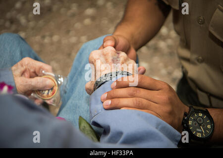 Sgt Henry Cisneros, ein Marine Corps Forces, Pacific Hotel Schreiber, gab sein Denkmal Armband Pfc. Jimmy Keep an der Honolulu International Airport Oahu, Hawaii, 17. März 2015. 88-j hrige Weltkrieg Marine vereinbart, verlassen das Denkmal-Armband in den Sand der Iwo Jima, Cisneros Freund, Sgt. Matthew Abbate, zu Ehren, sein Leben in Afghanistan, Dezember 2010 verloren. Halten Sie kehrt nach Iwo Jima zum ersten Mal seit kämpfen dort im Rahmen des 4. Marine Division-70 Jahren. (Foto: U.S. Marine Corps CPL. Matthew J. Bragg) Marines grüßen WWII Tierarzt 150316-M-DP650-077 Stockfoto