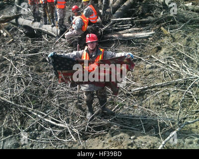 Nach dem ziehen auf einen dünnen roten Faden begraben in einem Haufen von Schutt aus dem Oso Erdrutsch, Staff Sgt Michael Cohan aus dem 141. logistischen Bereitschaft Geschwader aus Fairchild Air Force Base in Washington deckt einen zerfetzten amerikanischen Flagge und stellt es stolz. (Foto: Luftwaffe Msgt. Kevin Borden) OSO Schlammlawine 140501-Z-RI264-001 Stockfoto