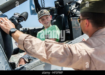 Ein Kind sitzt im Cockpit einer AH-1W Super Cobra zugewiesen, Marine schwere Hubschrauber Geschwader (HMH) 464 beim US Marine Corps 1st Lt. William C. Wiggins, Recht, Pilot bei HMH-464, spricht bei einem Red Bull Global Rallycross (GRC)-Event auf der Marine Corps Air Station New River, North Carolina, 5. Juli 2015. Im Wettbewerb auf einer.993-Meilen-Strecke, war die längste in der Reihe Geschichte, das Red Bull GRC-Ereignis das erste Motorsport-Rennen auf einer aktiven Militärbasis stattfinden. (Foto: U.S. Marine Corps Sgt. Christopher Q. Stone, MCIEAST MCB CAMLEJ Bekämpfung der Kamera/freigegeben) Red Bull Global Rallycross - MCAS New River 15 Stockfoto