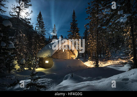 Kleines Ferienhaus im schönen Schneewald Mond nachts Stockfoto