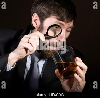 Porträt von hübscher junger Geschäftsmann Weinbrand durch Lupe betrachten Stockfoto