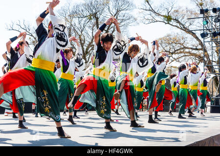 Japanische yosakoi Dance Festival. Männer und Frauen tanzen auf der Bühne in bunten Kostümen. Low Angle View entlang der Tänzer. Arme angehoben. Stockfoto