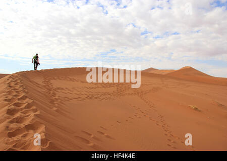 Ein Tourist ist das Klettern einer Sanddüne in der Wüste von Sossusvlei, Namibia Stockfoto