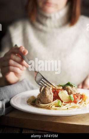 Frau Essen Spaghetti mit Fleischbällchen vertikale Stockfoto