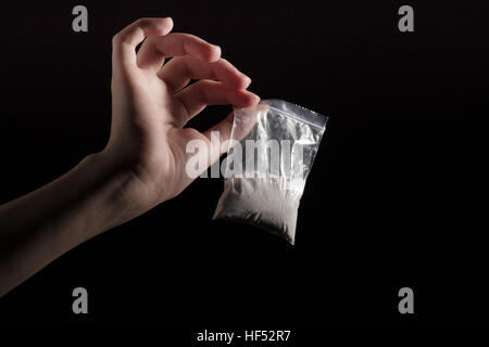 Paket mit weißen Betäubungsmittel in der Hand auf schwarzem Hintergrund Stockfoto