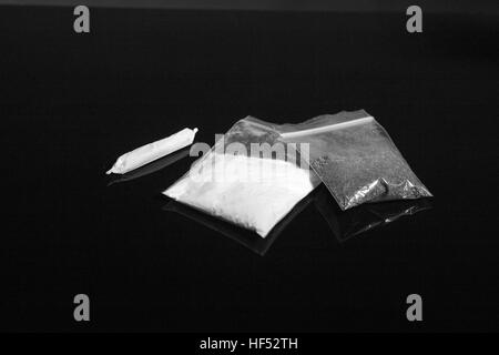 Betäubungsmittel-Packs und gemeinsame Marihuana auf schwarzem Hintergrund, Monochrom Stockfoto