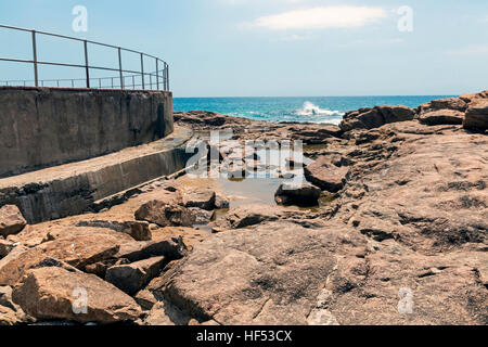 Nassen Felsenküste am Scottburgh Strand gegen Ozean weißen Wolken und blauer Himmel Küstenlandschaft in Südafrika Stockfoto