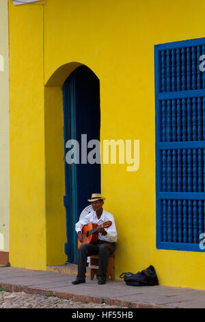 Mann sitzt in einem bunten Ort in Trinidad, Kuba, Gitarre spielen Stockfoto