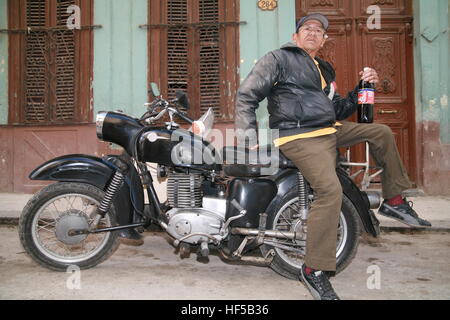 Ein älterer Mann sitzt auf seinen Oldtimer Motorrad mit einer Flasche kubanischen Cola (Tu Cola), Havanna, Kuba, Karibik, Amerika Stockfoto