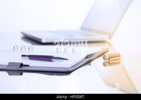 Geschäftsmann schreiben Sie eine kurze Notiz auf geöffneten Notizbuch mit Stift und Gläser. Stockfoto