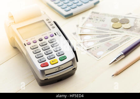 Kreditkarten-Terminal oder EDC auf Kasse Holztisch im Store mit japanischen Banknoten, Kugelschreiber, Bleistift und Taschenrechner. Stockfoto