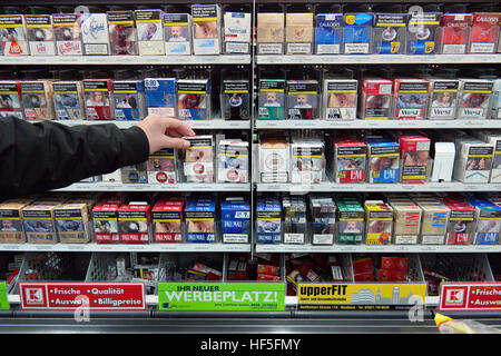 Zigaretten in einem Supermarkt mit Bildern auf Zigarettenschachteln, die Gefahren des Rauchens zu illustrieren Stockfoto