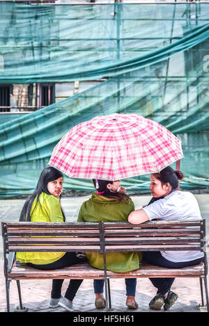 Junge Frauen sitzen auf einer klassischen Bank in Hanoman Dhoka plaza, Durbar Square, Kathmandu, Nepal. Stockfoto