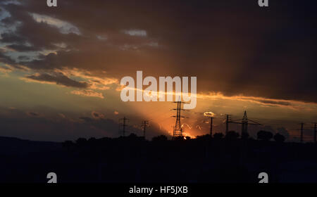 Sonnenuntergang unter dem Hochspannungs-Turm im Hintergrund Stockfoto
