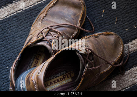 Ein paar eingelaufene Bordschuhe sitzt auf einem Flur Teppich. Stockfoto