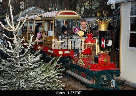 Dänemark, Kopenhagen, Tivoli-Gärten, Weihnachten, Kind mit Vater auf der Kindereisenbahn fahren in der Dämmerung Stockfoto