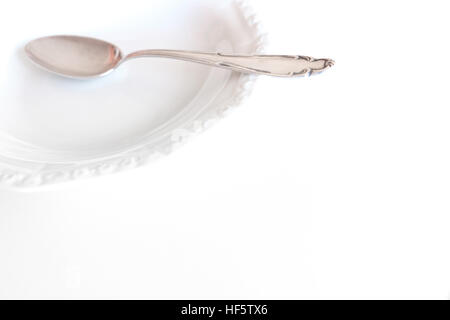 leeren Teller mit silbernen Löffel isoliert auf weißem Hintergrund Stockfoto