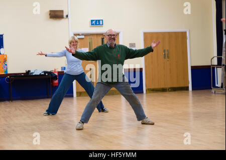 Zwei mittleren Alter Menschen - Mann und Frau, Teilnahme an einem Tai Chi Übung Workshop Lektion Klasse bei Tregaron Memorial Hall, ländlichen Ceredigion, Wales UK Stockfoto