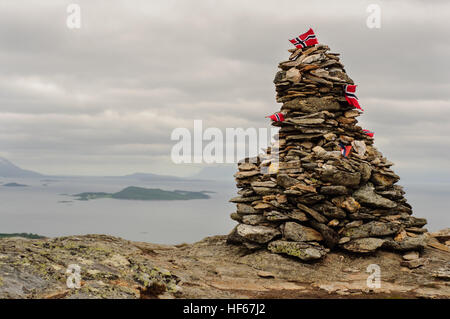 Stapel von Steinen mit Norwegen Fahnen auf Bergspitze in Lofoten, Norwegen. Berge im Hintergrund Stockfoto