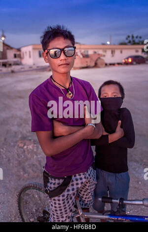 Ein kleiner Junge emuliert sein älteren Bruder durch das Spielen des harte Kerl an Bogo City, Insel Cebu, Philippinen. Stockfoto