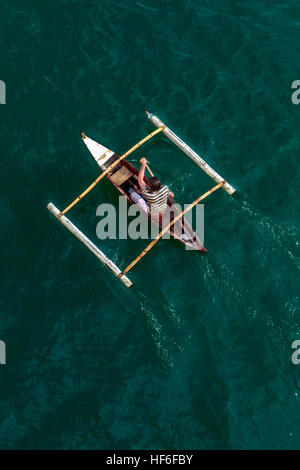 Ein Filipino Mann Paddel seine hausgemachte Ponton-Ausleger-Kanu in Cebu Hafen, Cebu City, Insel Cebu, Philippinen. Stockfoto