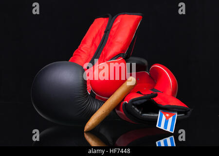Rote und schwarze Boxhandschuhe und Luxus kubanische Zigarren auf schwarzem Glastisch. Stockfoto