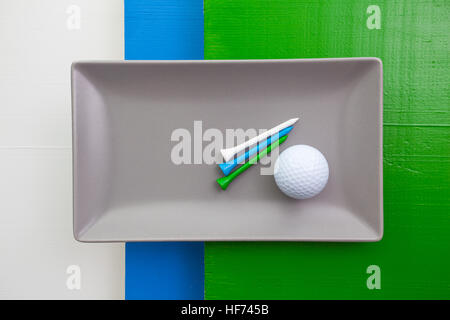 Graue Keramik Teller mit Golf-Ausrüstungen auf über weißen, blauen und grünen Holztisch, Rechteck Schale Stockfoto