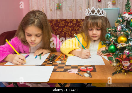 Zwei Mädchen schreiben Weihnachtsgruß Brief am Tisch zu Hause Stockfoto
