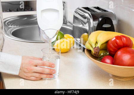 Mann füllt Glas mit sauberem Wasser aus Filter Krug Stockfoto