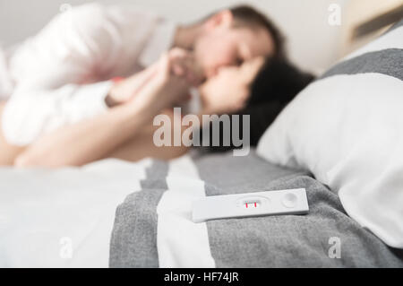 Positiven Schwangerschaftstest liegt auf dem Bett. Glückliches Paar genossen auf Hintergrund Stockfoto