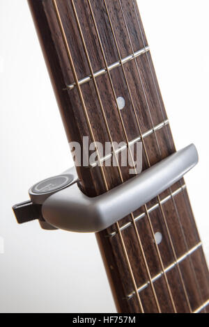 G-Klammer Typ Gitarre Capo positioniert zwischen den Bünden auf einem Palisander Hals, Stockfoto