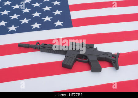 Schwarzes Spielzeug Sturmgewehr gegen US / amerikanische Flagge / Stars & Stripes gesetzt. Für US-Waffengewalt, US-Waffenrecht, Terrorismus, Chicago-Verbrechen, Arsenal Stockfoto