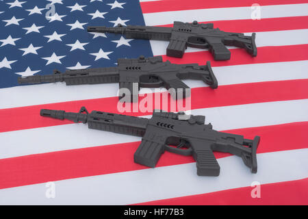 Schwarze Spielzeuggewehre gegen US-/amerikanische Flagge/Stars & Stripes. Für US-Waffengewalt, US-Waffenrecht, Terrorismus, Chicago-Verbrechen, Arsenal. Stockfoto