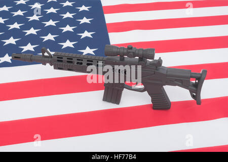 Schwarzes Spielzeug Sturmgewehr gegen US / amerikanische Flagge / Stars & Stripes gesetzt. Für US-Waffengewalt, US-Waffenrecht, Terrorismus, Chicago-Verbrechen, Arsenal Stockfoto