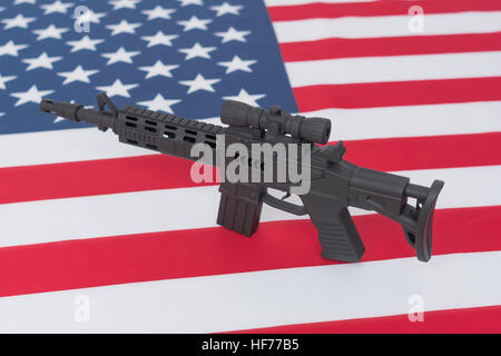 Schwarzes Spielzeug Sturmgewehr gegen US / amerikanische Flagge / Stars & Stripes gesetzt. Für US-Waffengewalt, US-Waffenrecht, Terrorismus, Chicago-Verbrechen, Arsenal. Stockfoto