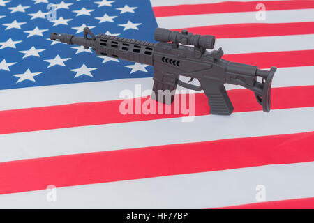 Schwarzes Spielzeug Sturmgewehr gegen US / amerikanische Flagge / Stars & Stripes gesetzt. Für US-Waffengewalt, US-Waffenrecht, Terrorismus, Chicago-Verbrechen, Arsenal Stockfoto