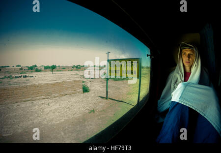 Ein junger Mann auf eine einsame Reise durch die Wüste von Rajasthan, sieht die Welt aus dem Zugfenster. Stockfoto