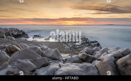 Sonnenuntergang über dem Meer in Zadar/Kroatien eine lange Belichtung, so dass die Wellen einen sanften Nebel erzeugen. Stockfoto