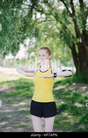 Junge Fitness Frau Übung vor Lauf. Sportler stehen unter Baum. Stockfoto