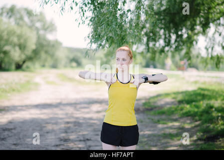 Junge Fitness Frau Übung vor Lauf. Sportler stehen unter Baum. Stockfoto