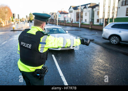 Ein PSNI Straße Polizei-Offizier kennzeichnet sich entgegenkommenden Fahrer während einer zufälligen Alkohol am Steuer-Checkpoint in Belfast. Eine betrunkene Mutter tun die Schule laufen nach eine feuchtfröhliche Mittagessen unter den Hunderten von Fahrern mit neuen Polizeibeamten durchzuführen zufällige Atemtests in Nordirland gefangen war. Stockfoto