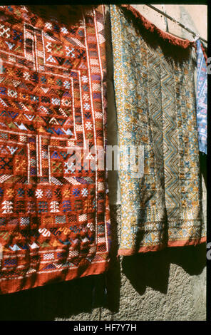Dieses Bild zeigt Teppiche, die in einem Souk in der Medina von Marrakesch, Marokko, verkauft werden, und hebt die lebendige Marktkultur und traditionelle marokkanische Handwerkskunst hervor. Stockfoto