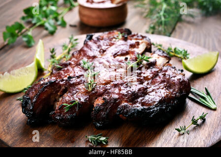 Grill, gegrillte Schweinerippchen auf Holzbrett, geringe Schärfentiefe Stockfoto