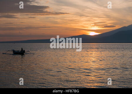 Sonnenuntergang mit Fisher Mann in einem Boot im Meer in der Nähe von Gili Air indonesischen Insel Angeln Stockfoto