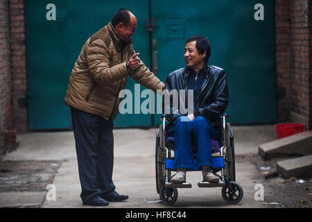 (161228)--HENGSHUI, 28. Dezember 2016 (Xinhua)--Wang Mingchen (L) begleitet Li Jianguo für einen Outdoor-Spaziergang in Taocheng Bezirk in Hengshui Stadt, Nordchinas Provinz Hebei, 28. Dezember 2016. Wang Mingchens linke Bein amputiert wurde wegen eines Autounfalls im Jahr 2000. Unterdessen litt Li Jianguo, Wang Mingchens Nachbar und ehemaliger Arbeitskollege, hohe Querschnittslähmung verursacht durch einen Unfall im Jahr 2001. Als er die meisten pflegebedürftig war, ließ ihn Li es Eltern starben in Folge und seine Frau mit ihrem Kind. Gefühl für Li, Wang versprach, ihn sein ganzes Leben lang kümmern, und er hat geklebt zu seinem Versprechen fo Stockfoto