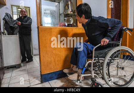 (161228)--HENGSHUI, 28. Dezember 2016 (Xinhua)--Wang Mingchen (L) wäscht Kleidung und spricht mit Li Jianguo am Haus von Li Jianguo in Taocheng Bezirk in Hengshui Stadt, Nordchinas Provinz Hebei, 28. Dezember 2016. Wang Mingchens linke Bein amputiert wurde wegen eines Autounfalls im Jahr 2000. Unterdessen litt Li Jianguo, Wang Mingchens Nachbar und ehemaliger Arbeitskollege, hohe Querschnittslähmung verursacht durch einen Unfall im Jahr 2001. Als er die meisten pflegebedürftig war, ließ ihn Li es Eltern starben in Folge und seine Frau mit ihrem Kind. Gefühl für Li, Wang versprochen, ihn sein ganzes Leben lang kümmern, und er hat s Stockfoto