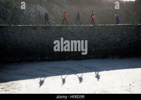 Besucher von Llanddwyn Island vor der Küste von Anglesey genießen die angenehmen Bedingungen, wie sie über den Deich am Hafen Fuß Stockfoto