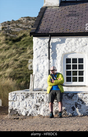Ein Mann genießen die warmen Temperaturen und strahlendem Sonnenschein auf Llanddwyn Island vor der Küste von Anglesey vor dem Piloten auf dem Land in einem warmen Tag im Dezember Stockfoto