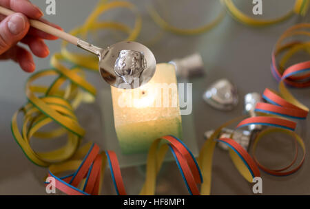 Hannover, Deutschland. 29. Dezember 2016. ILLUSTRATION - ein Stück Blei Schmelze über eine Kerze in Hannover, 29. Dezember 2016 wird. Molybdomancy - Blei Gießen - ist eine beliebte Tradition in Europa. Kleine Stücke von Blei sind auf einem Löffel über einer Kerze geschmolzen und dann in Wasser, neugierige und bizarre Formen, die an das kommende Jahr vorhersagen sollen gegossen. Foto: Peter Steffen/Dpa/Alamy Live News Stockfoto